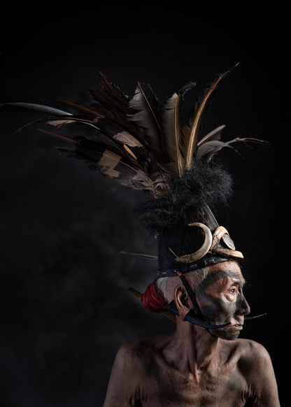 Person wearing a traditional headdress with feathers against a black background